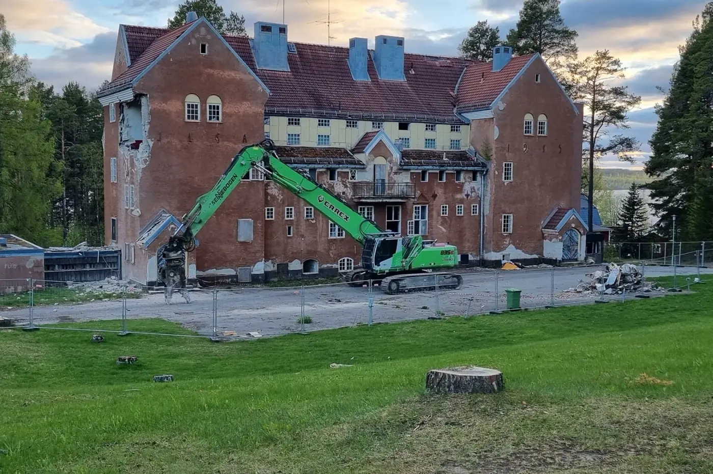 CRREX grävmaskin river äldre flerbostadshus i Bräcke vid solnedgång