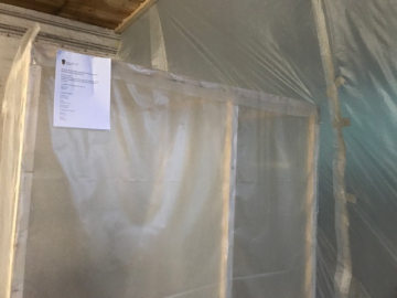 Arbetsplats under asbestsanering med trekammarsluss och glovebag-teknik för säker hantering