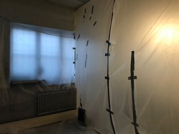 Skyddsplast täcker arbetsytan under asbestsanering för att förhindra spridning av asbestdamm.